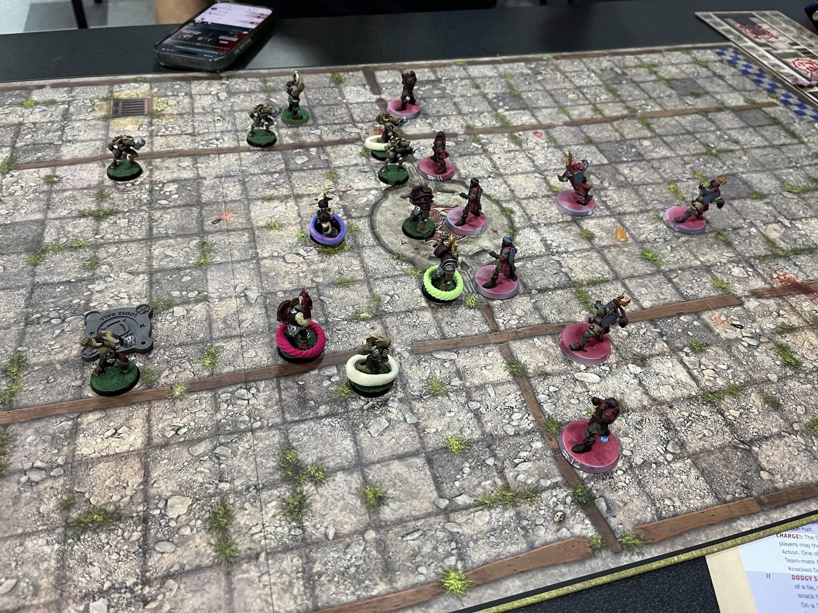 Overhead view of the stone pitch mid-match, Grenadiers on pink bases facing the Chaos Chosen