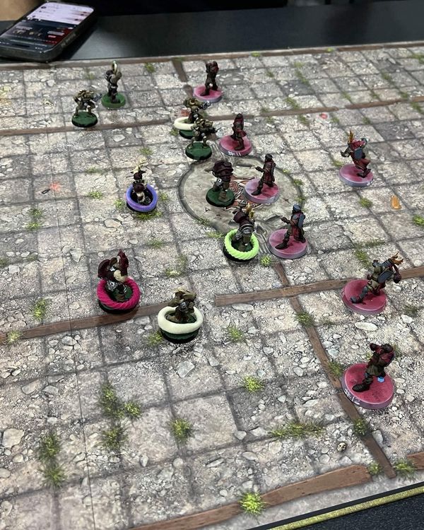 Overhead view of the stone pitch mid-match, Grenadiers on pink bases facing the Chaos Chosen