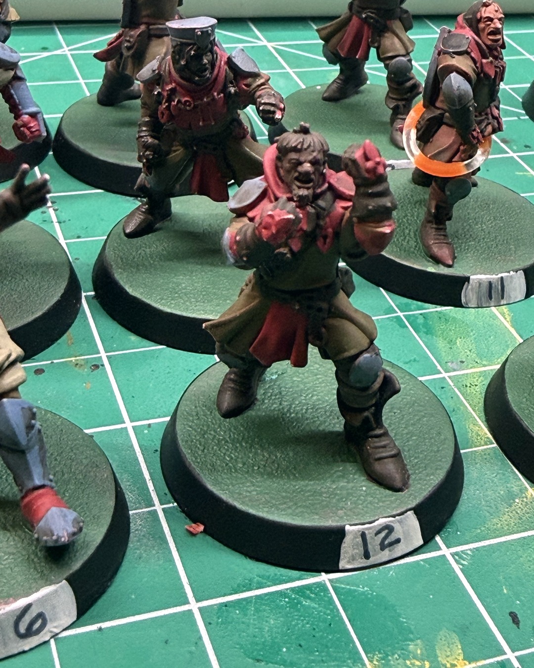 Painted Holy Hand Grenadiers squire number 12 mid-shout on a green base with a fresh white number label on the black rim, squires 11 and 6 around him