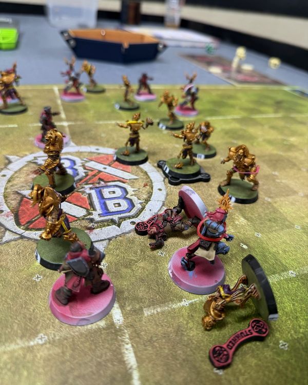 A Grenadiers knight standing over a Stunned Tomb Kings player, gold Tomb Guardians looming beyond