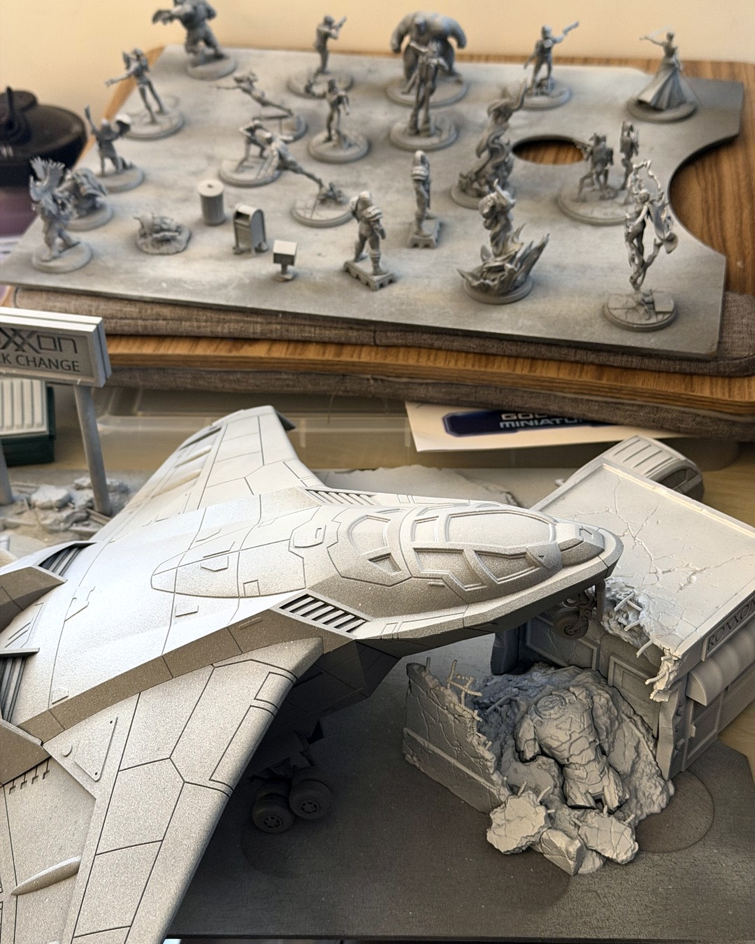 Grey-primed Quinjet terrain nose in the foreground over the Crashed Sentinel terrain, a tray of primed Crisis Protocol minis soft in the background