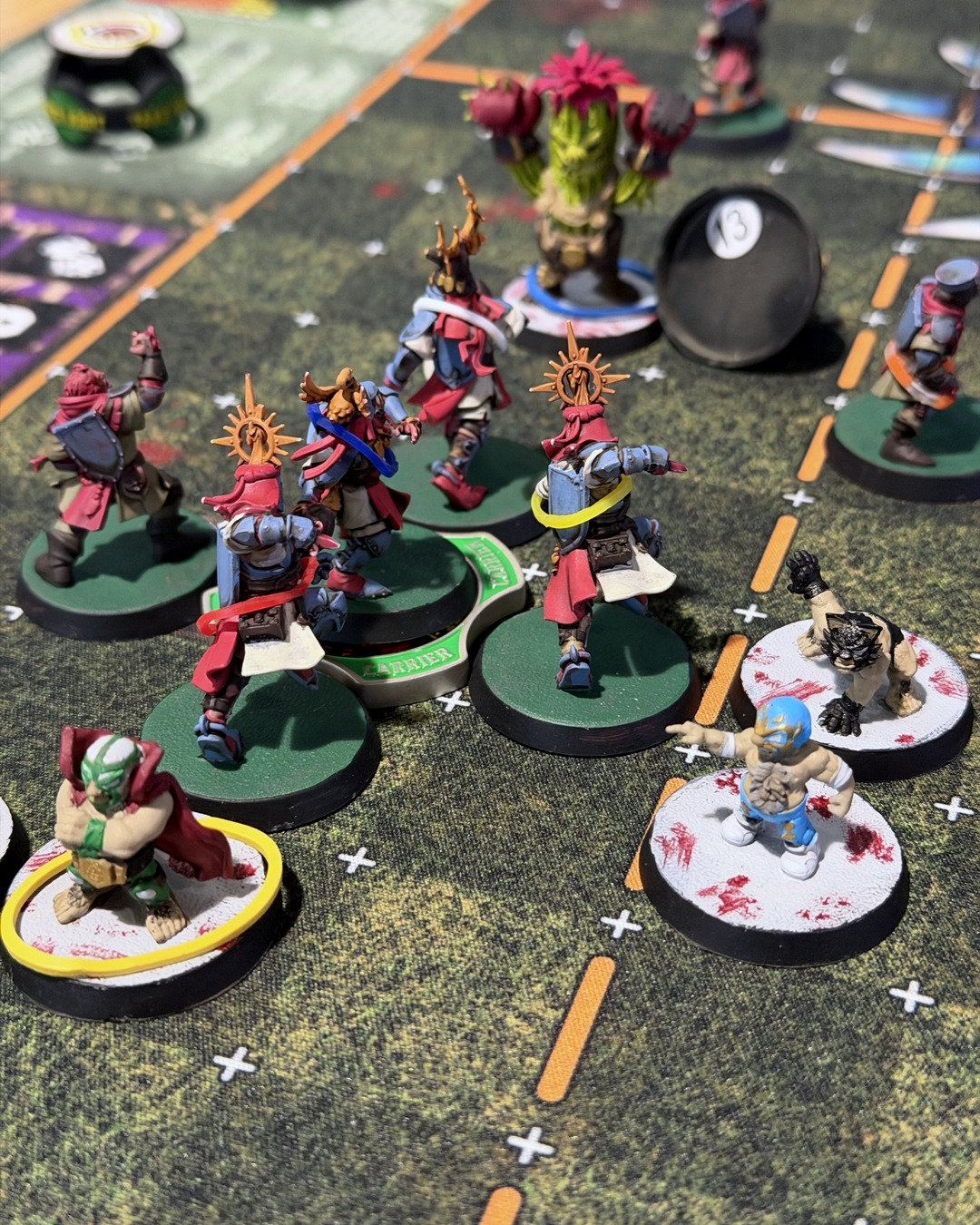 Holy Hand Grenadiers knights in red and slate blue pushing upfield in a cage, with luchador halflings around them