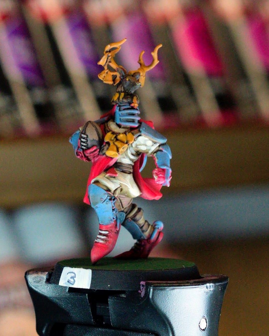 Knight number 3 in a gold stag-antler helm carrying the ball, slate blue armor, red cape and white tunic, on a painting handle