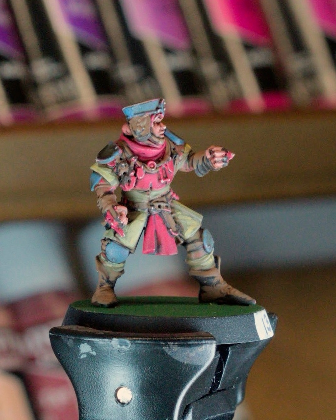 A squire in a blue cap and red scarf pointing forward, tan tunic with red tabard and leather straps, on a painting handle