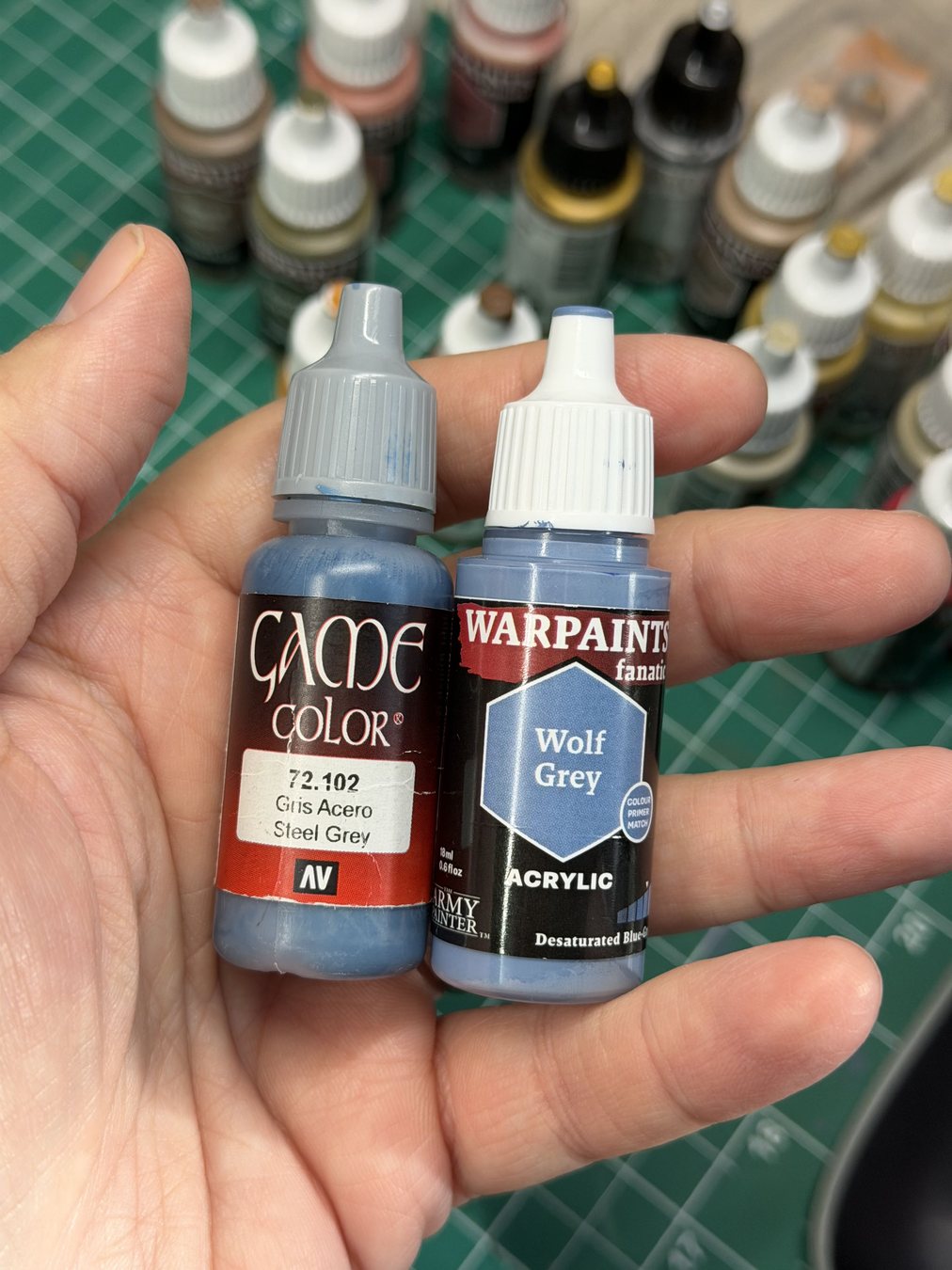 Vallejo Steel Grey and Warpaints Fanatic Wolf Grey bottles held in hand