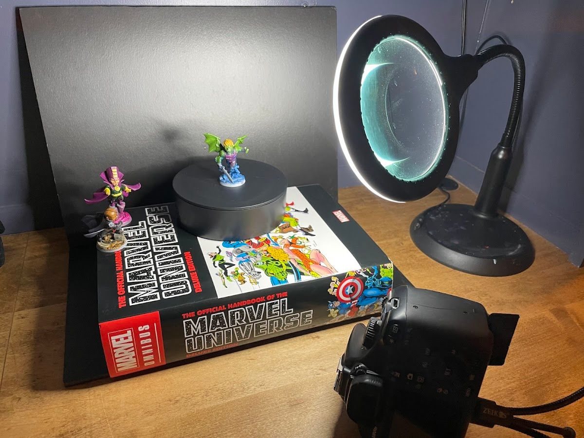 A desk setup with a light, a backdrop and a camera pointed at a mini