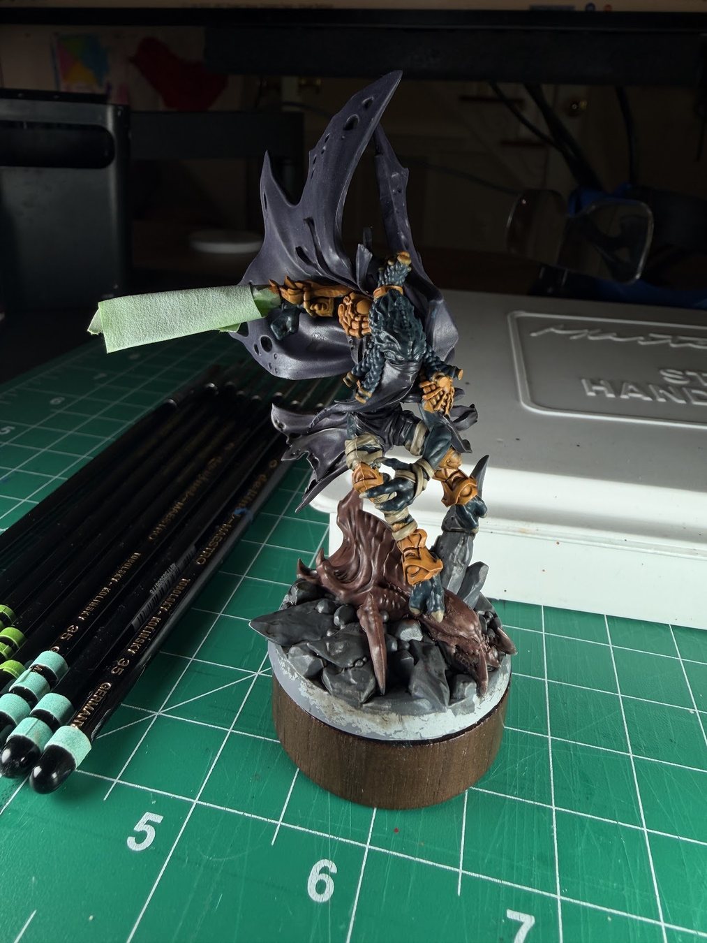 A work-in-progress Zeratul mini on a painting handle, next to a row of striped brushes